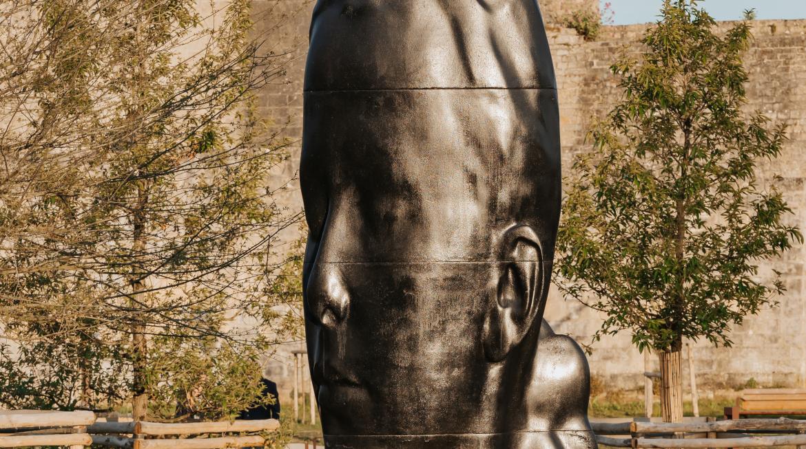 La tête de Lou, une tête de jeune fille en bronze, est posée sur l'herbe.